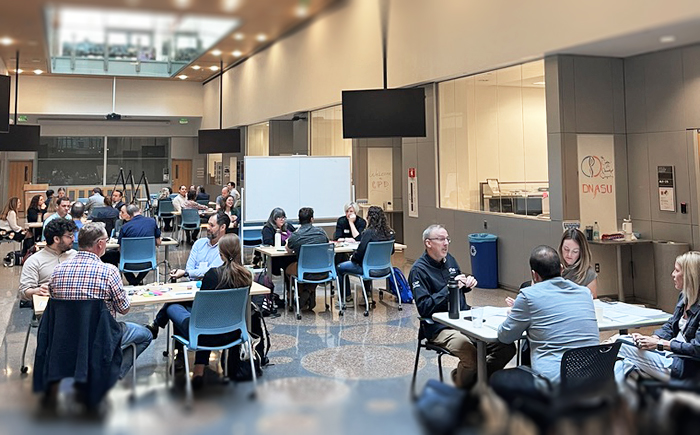 Many tables of people fill a hallway in a university building