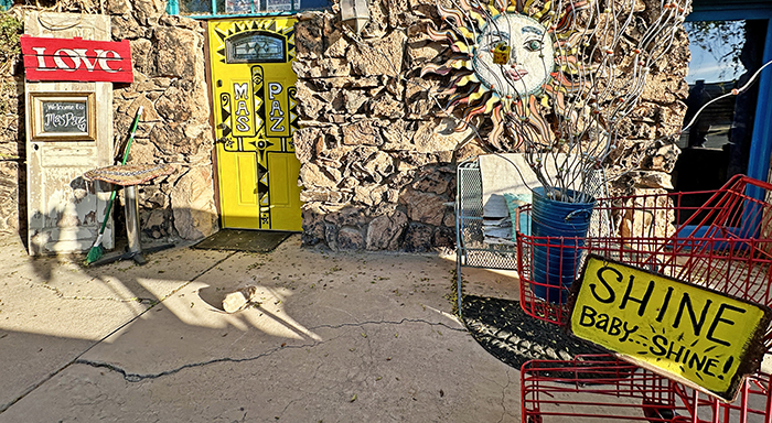 A colorful stone front building with bright signs and a yellow front door.