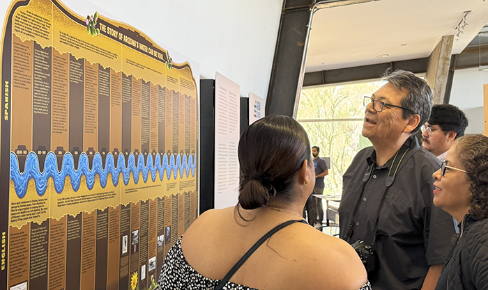 Lara-Valencia, and two exhibition visitors, observing and discussing the Arizona water history timeline artwork, located inside the Audubon Center exhibition space.