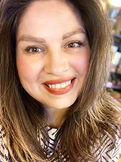 A woman with shoulder length brown hair smiles.