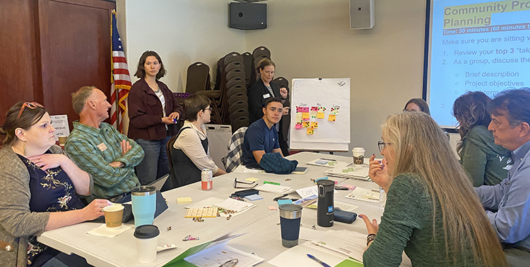 A group of people sits at a table in a conference room working.