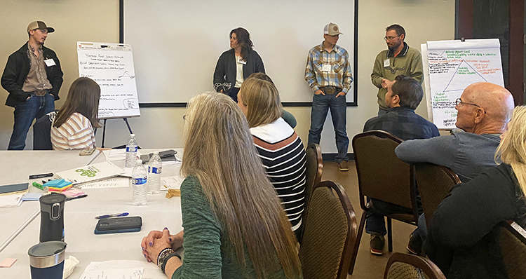 A group of people sits at a table in a conference room working.