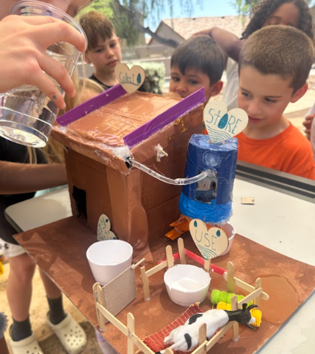 Young students look at a model of a rainwater harvesting system