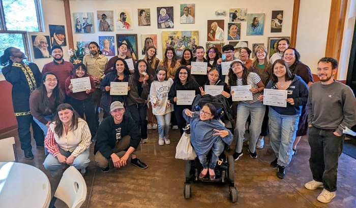 A large group of people hold graduation certificates up for the camera