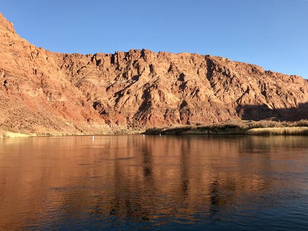 The Colorado River at Lee Ferry with the red rock walls of the canyon reflecting on deep water