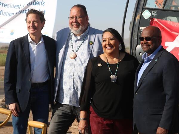 Four people stand smiling at a construction site