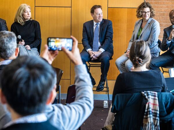 several people sit on a stage in a row for a panel