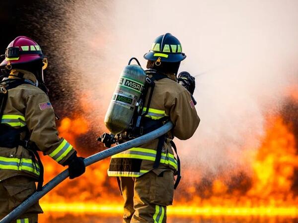 Two firefighters actively fight a fire