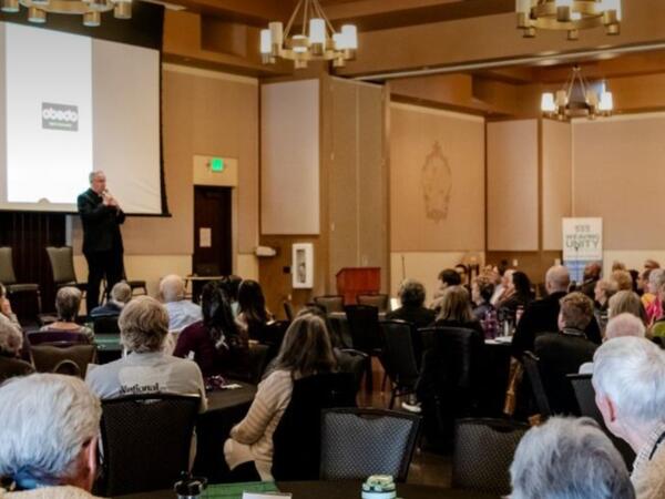 People sit in a room listening to a speaker