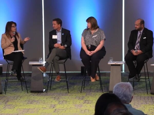 several people sit on a stage in a row for a panel