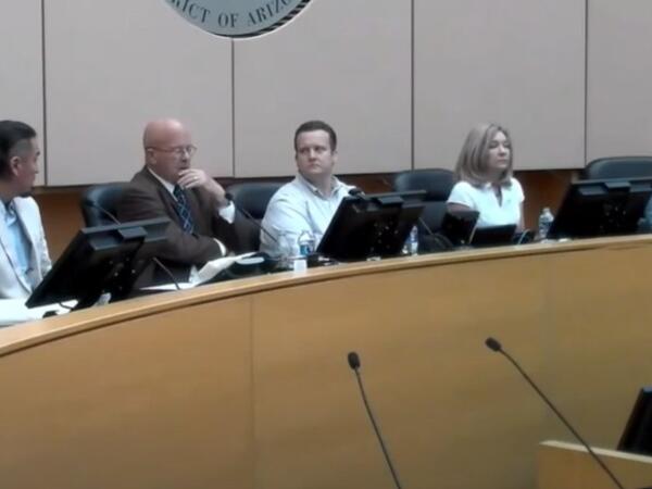 a panel of people sit in front of microphones