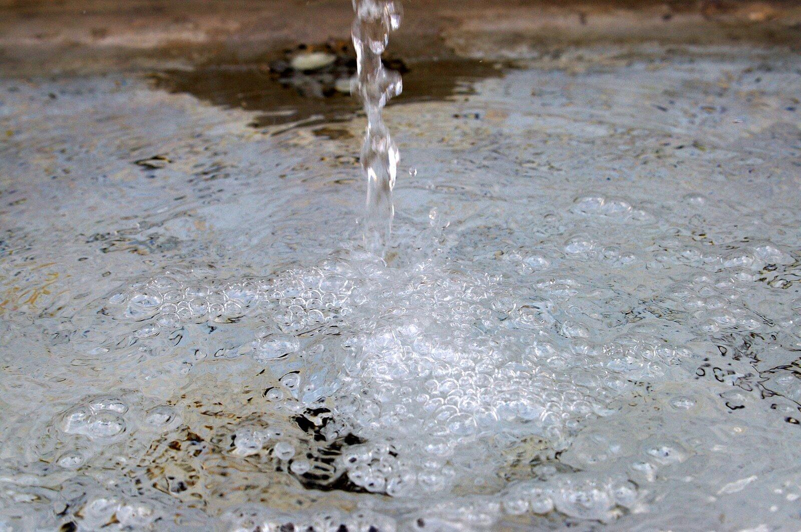 A stream of water spills into a pool, bubbling on the surface.