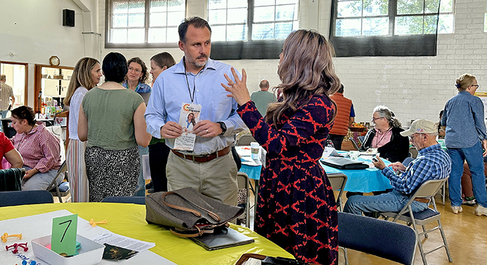 A man stands listening to a woman talking animatedly.