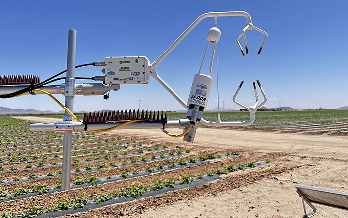 Two arms of a piece of scientific equipment in a desert ag field.