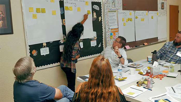 People present ideas on sticky notes to each other.