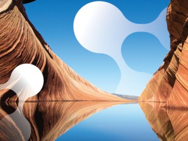 Red sandstone walls frame blue sky and reflecting water pool with large abstract water molecules superimposed.