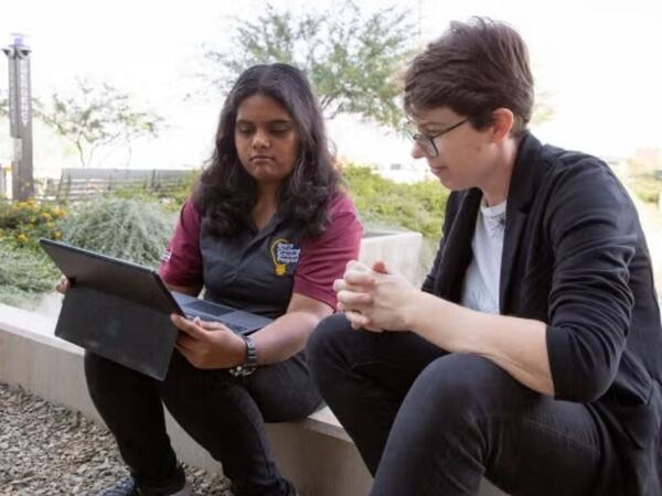 Researchers look at a laptop together outdoors