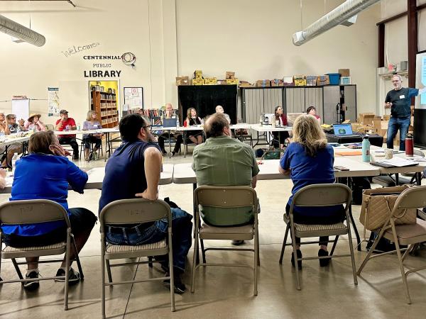 People sit around a U shaped table in a community center.