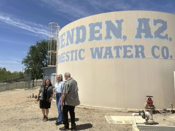 People stand in front of a large municipal water tank.