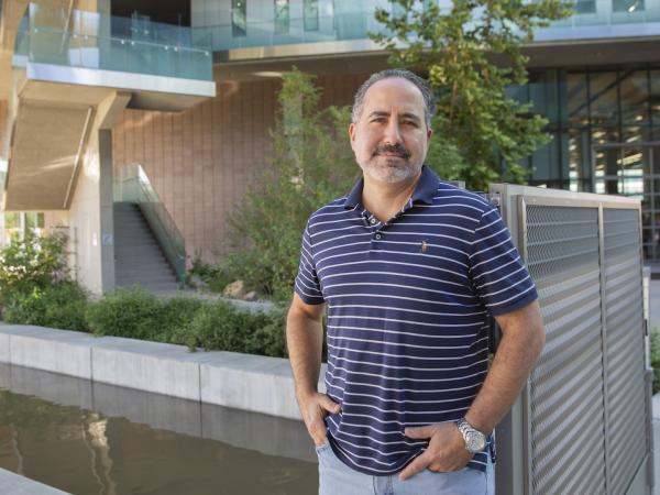 A man in a blue and white striped shirt with hands in pockets.
