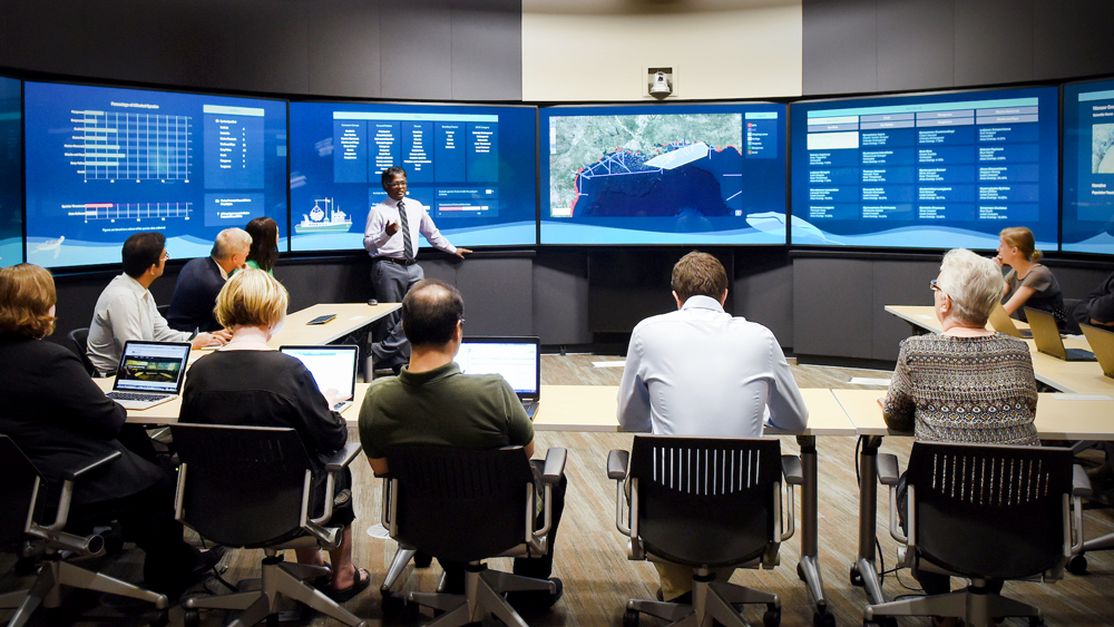 professionals in front of several horizontal monitors