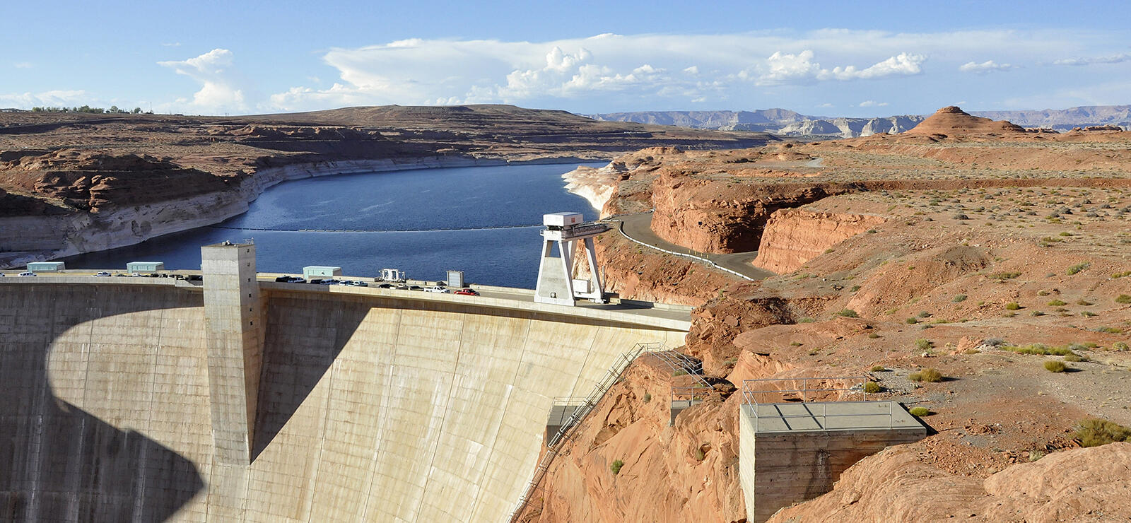 A large concrete dam in the middle of tall red sandstone formations with a river above. Photo by Paul Hermans.